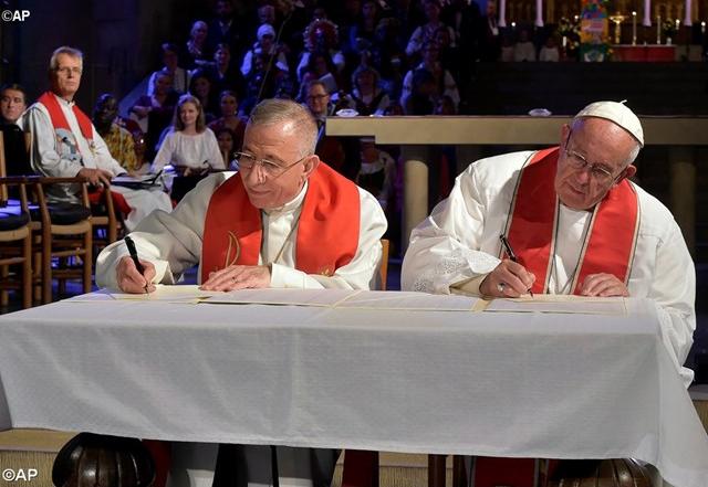 Pope Francis and Bishop Mounib Younan sign the Joint Statement in Lund's Cathedral - AP